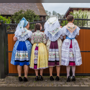 Frauen in niedersorbischer Tracht schauen über einen Zaun