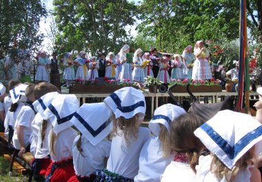 Kinder mit Kopftüchern sitzen vor einer Bühne in der Kita Spreewald. 2017 feierte die Kita Spreewald den 20. Geburtstag der Tanzgruppe Lutki.
