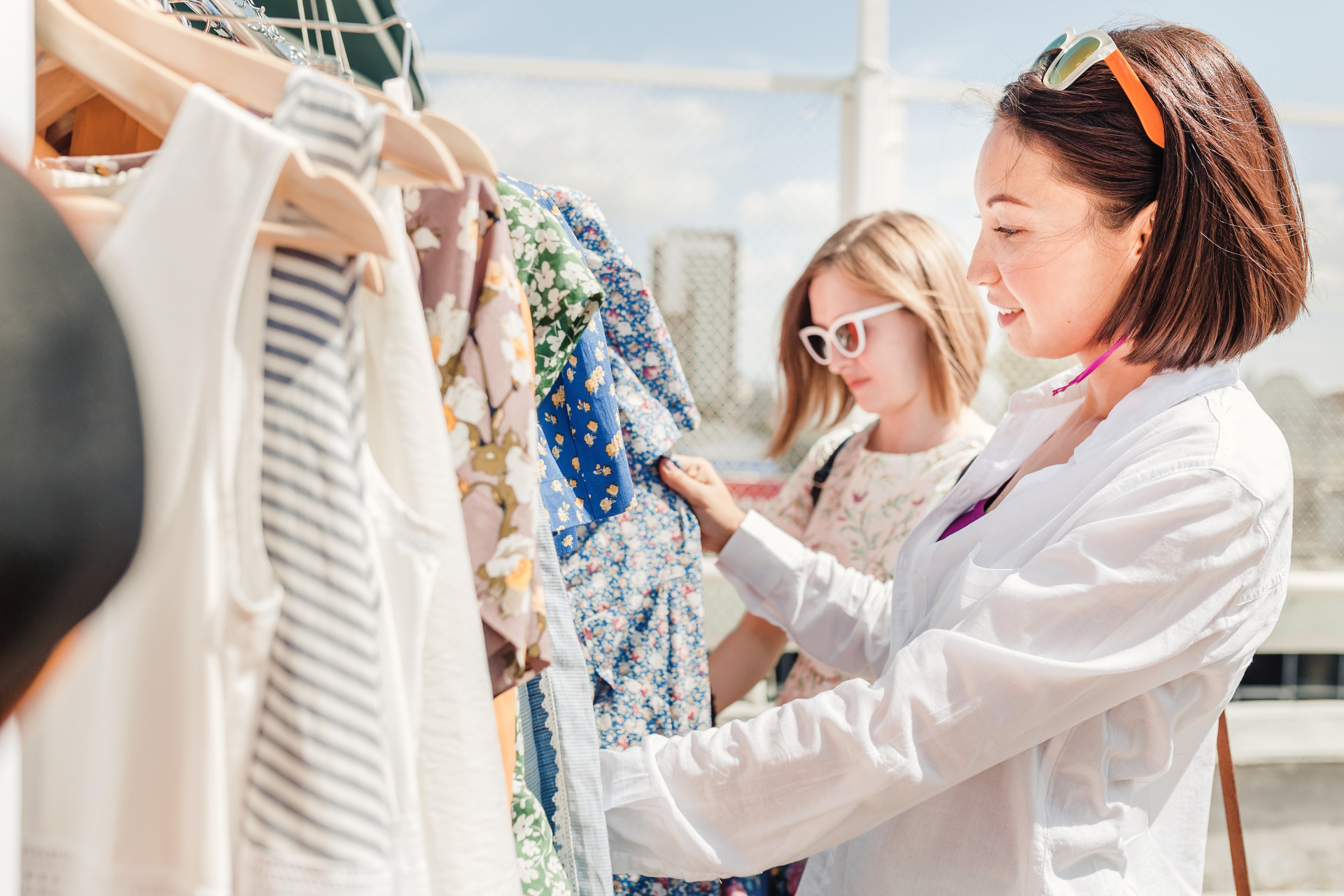 Two happy girls friends choosing and shopping fot clothes in boutique or outdoor flea market Two happy girls friends choosing and shopping fot clothes in boutique or outdoor flea market